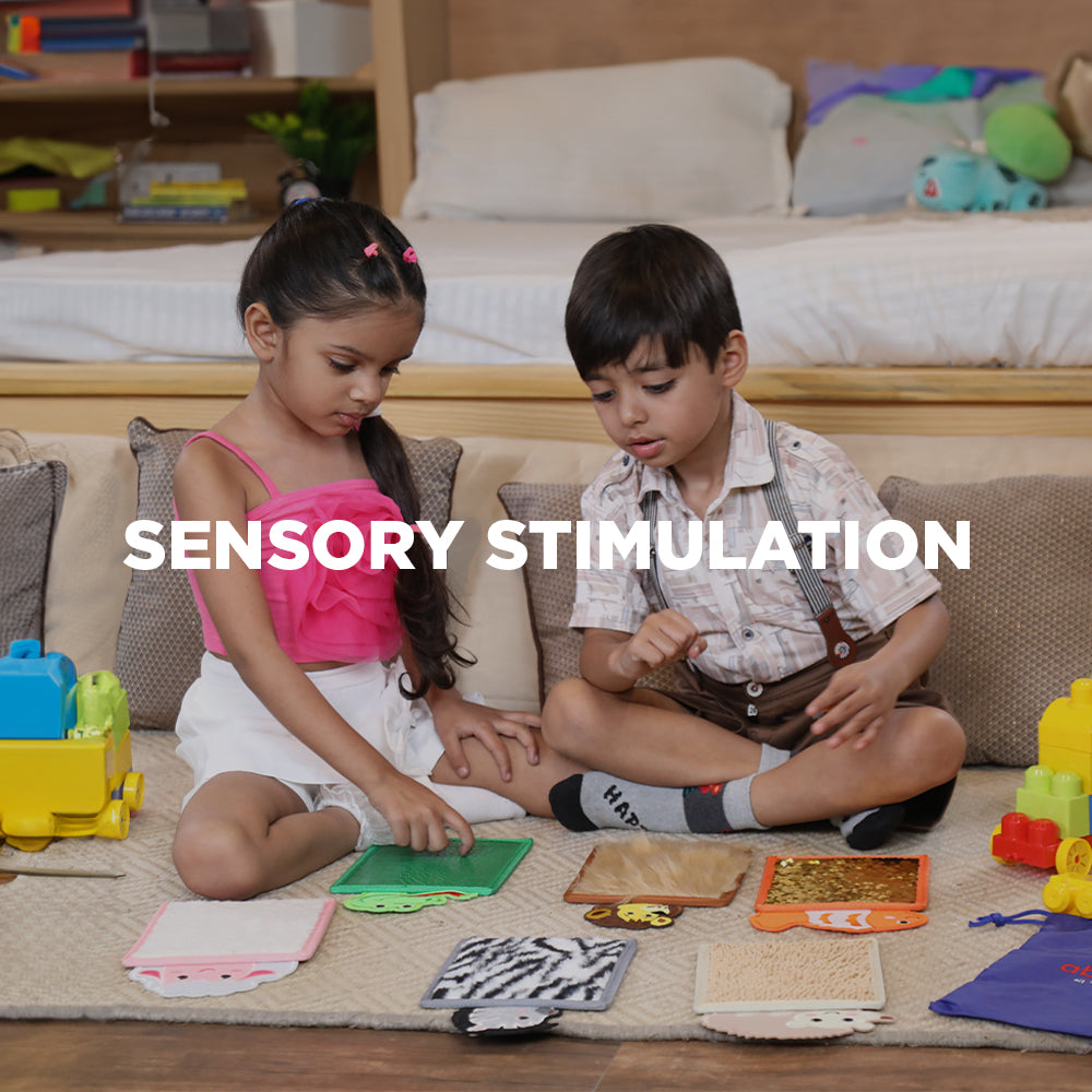 Two children sitting on floor exploring textured play mats and toys using sensory touch tools for kids