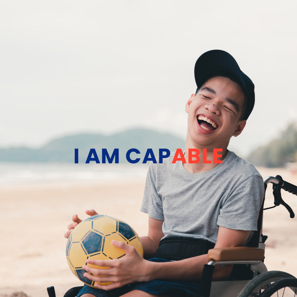 Smiling boy in wheelchair holding soccer ball on beach with I AM CAPABLE text showcasing sensory tools for children
