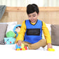 Blue Ableys weighted vest for kids with mesh front child sitting on bed playing with toy train