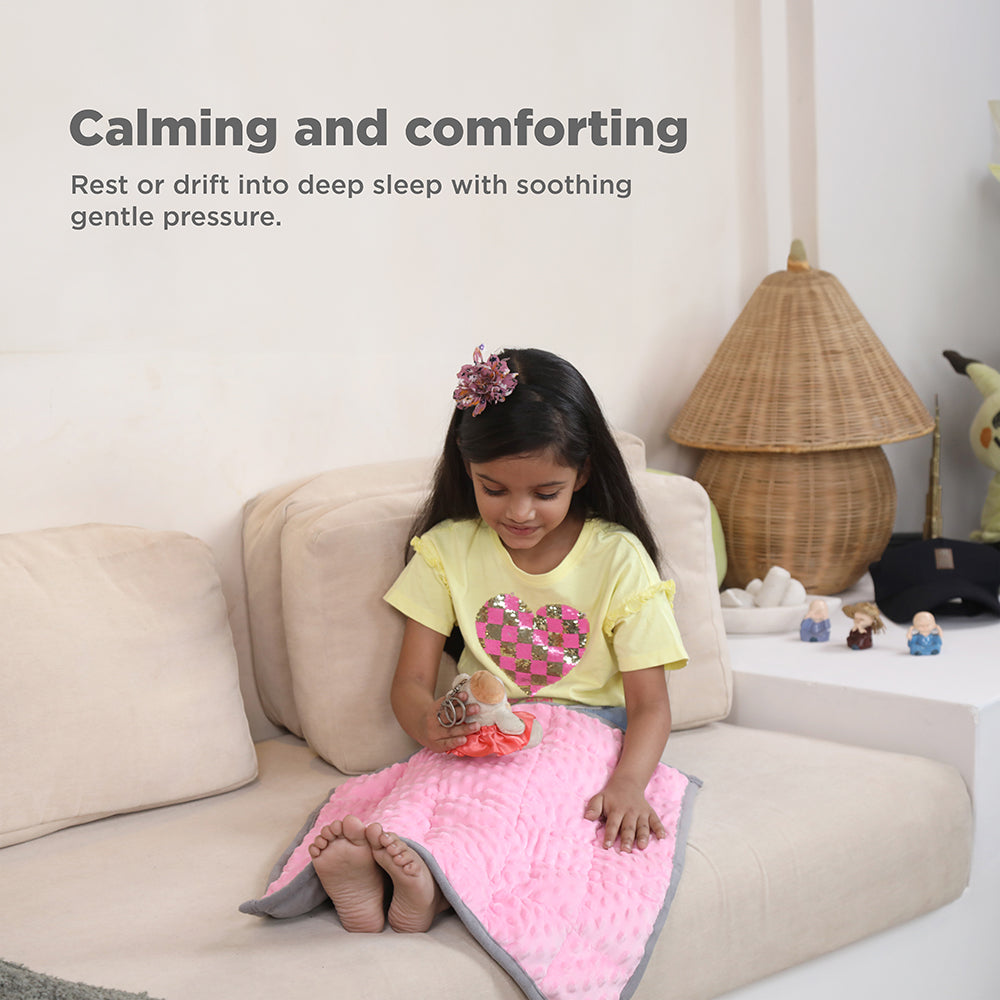 Ableys pink weighted lap pad for focus on a young girl sitting on a beige couch providing calming pressure