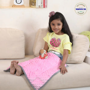 Ableys weighted lap pad for focus pink on a child sitting on couch with toy doll for calm focus