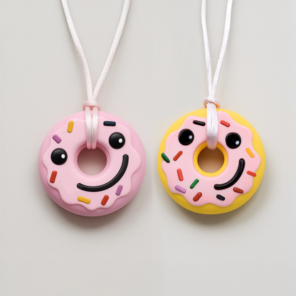 Two donut silicone chewable necklaces for sensory needs by Ableys in pink and yellow with smiling faces