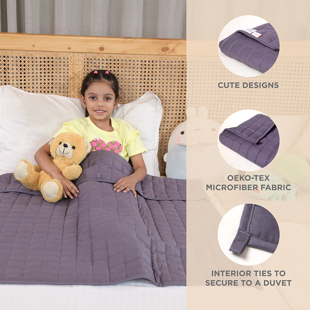 Ableys weighted blanket for kids in gray on bed with smiling girl holding teddy bear and quilted texture