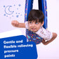 Child lying in blue patterned lycra sensory swing for kids looking playful with moon and stars