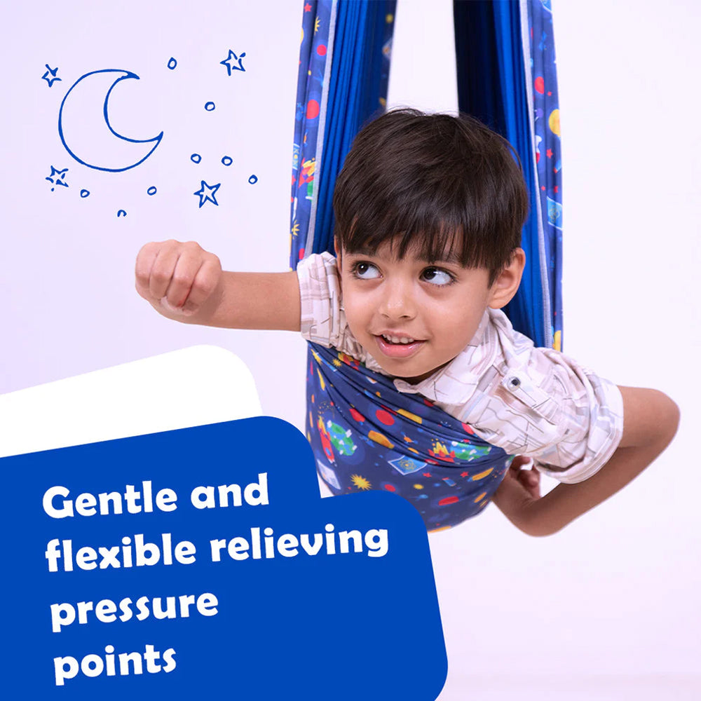 Child lying in blue patterned lycra sensory swing for kids looking playful with moon and stars