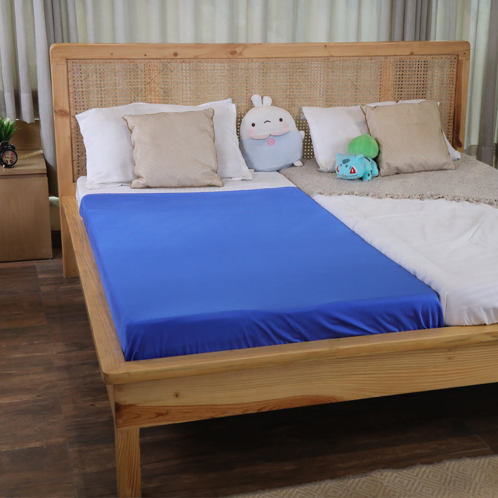 Ableys blue fitted compression bed sheet for sensory needs on a wooden bed with pillows and plush toys