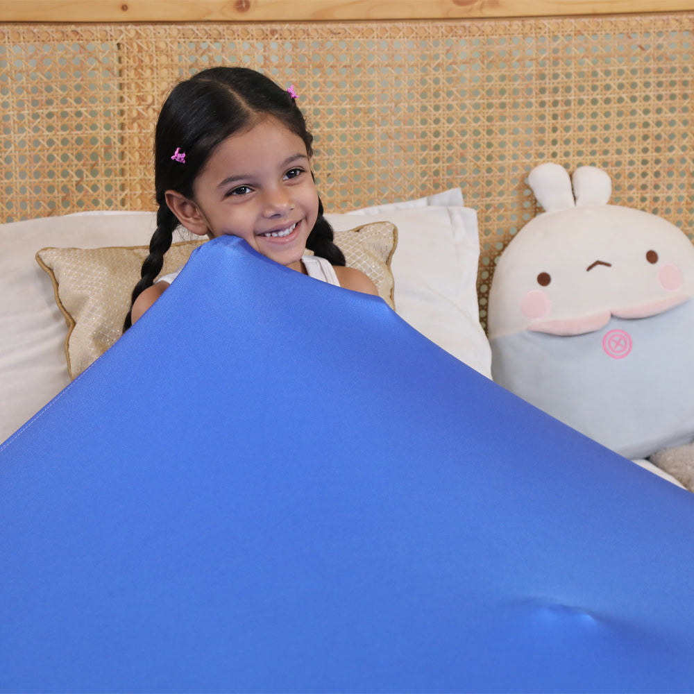 Ableys compression bed sheet for sensory needs on a smiling child under a blue stretchy calming hug sheet