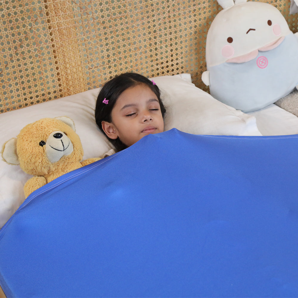 Ableys compression bed sheet for sensory needs shown on child asleep under blue snug calming sheet with teddy